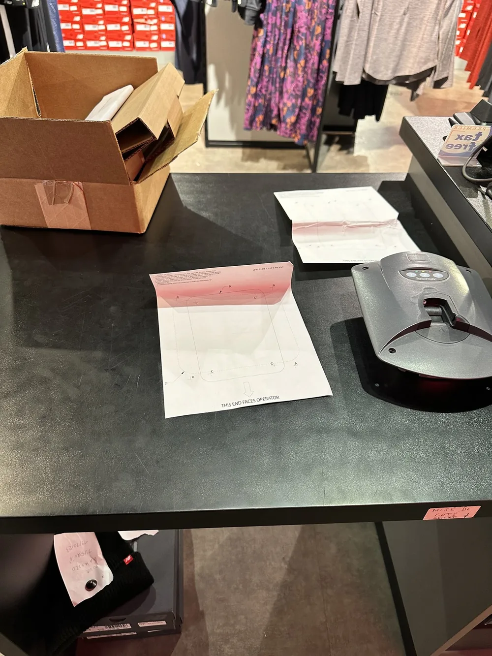 Détacheur Sensormatic vissé sur un comptoir d’encaissement, gabarits de perçage à côté