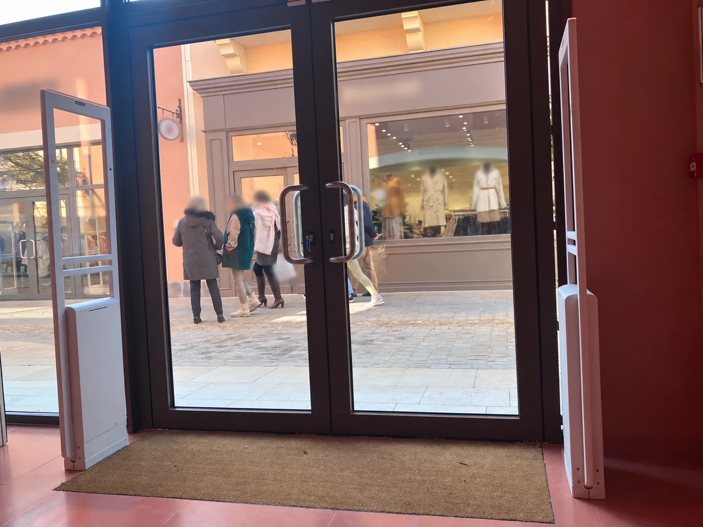 Vue large de deux portiques antivol blancs à l’entrée d’une boutique.